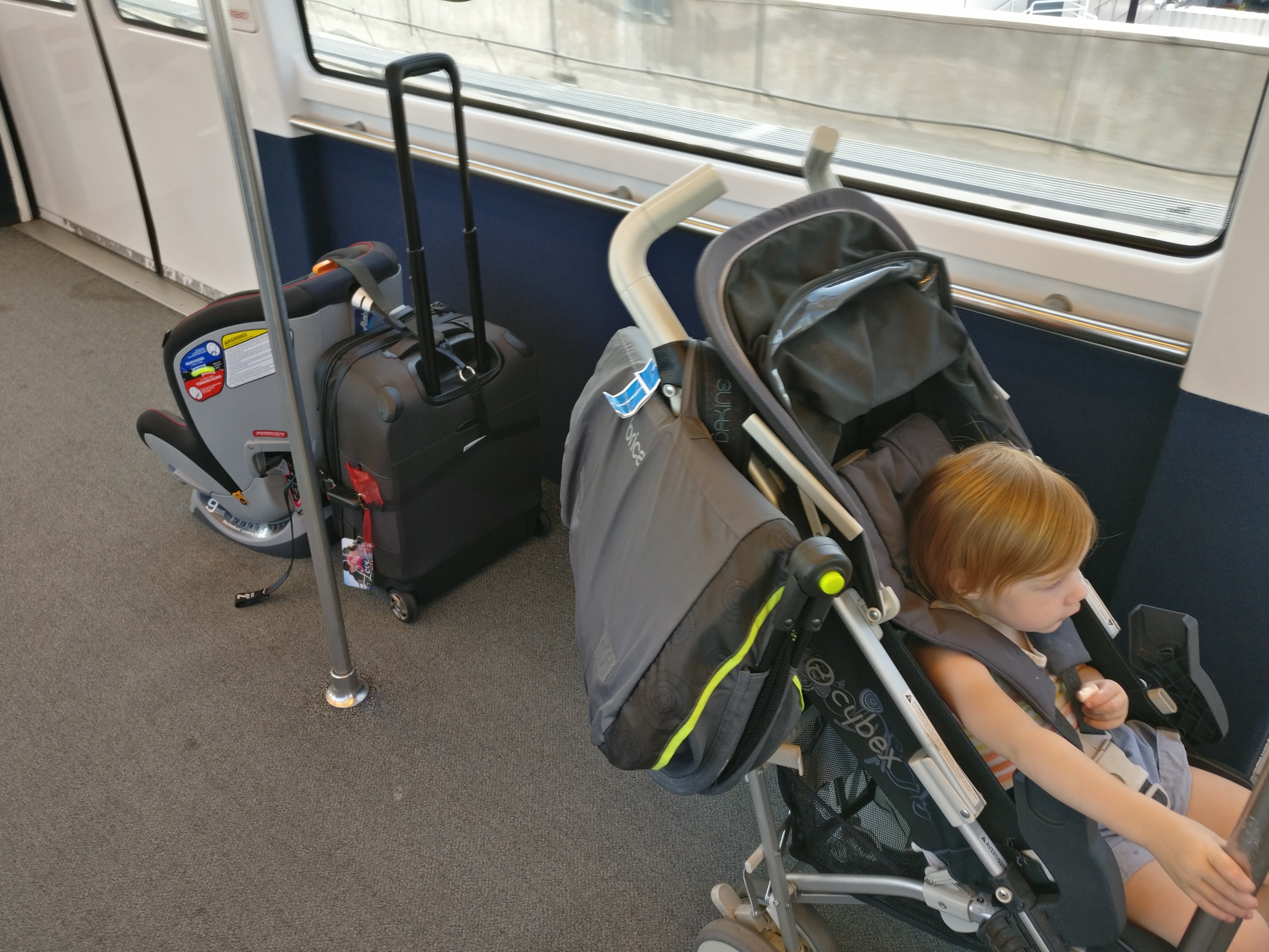 car seat strapped to suitcase, child in stroller