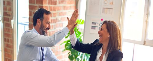 man and woman high five job well done in office