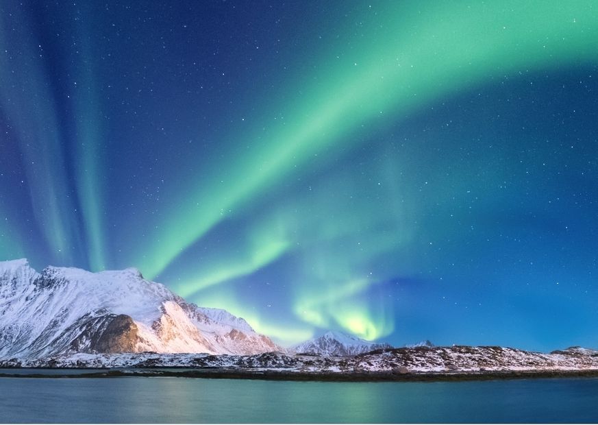 mountain and body of water in norway with northern lights streaking the sky