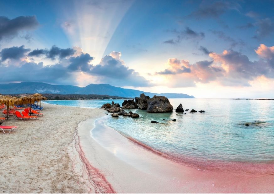 beach with pink sand and sun rays behind clouds